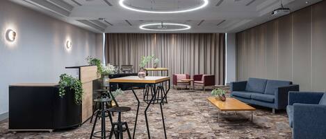 A modern conference room with a round table, bar stools, a sofa, and a coffee table.