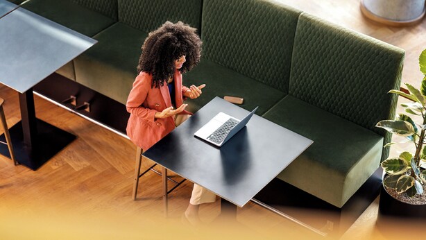 A person sitting on a green sofa with a laptop on a small table in front of them.