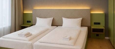 Habitación doble con dos camas, cada una con una almohada y una toalla doblada.