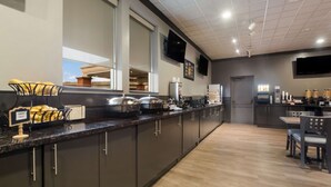 Une cuisine moderne avec des meubles de couleur sombre, un plan de travail en granit et un coin repas comprenant une table et des chaises.