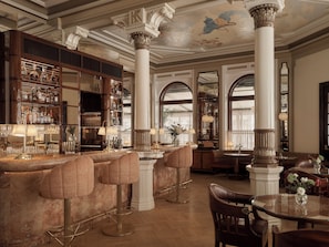 A bar area with high stools, a bar counter, and a large mirror.