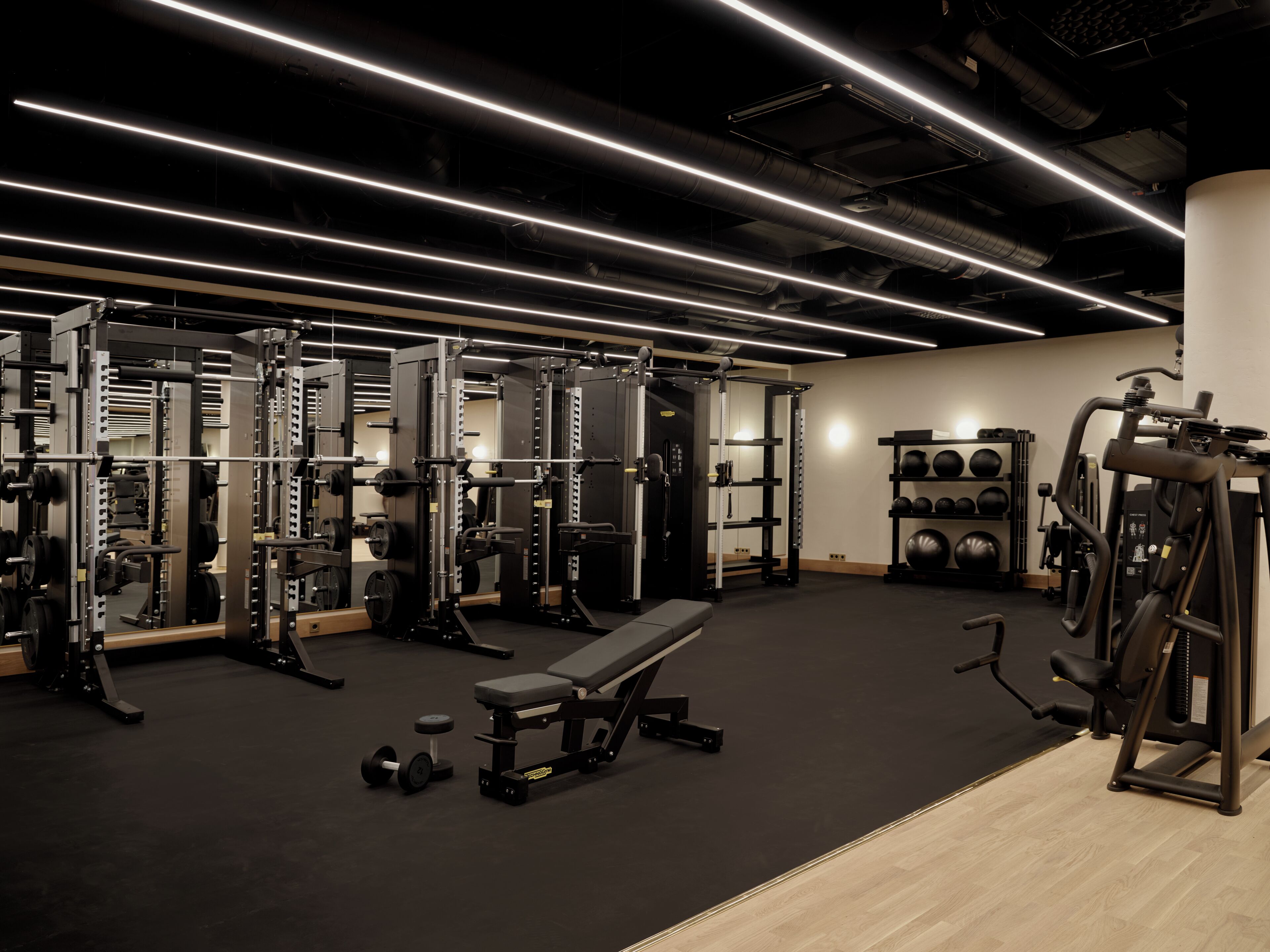 Une salle de sport équipée de matériel de musculation, de bancs et de ballons d’exercice.