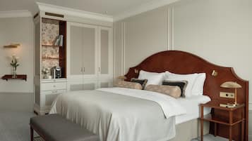 Une chambre à coucher avec un grand lit, une table de chevet en bois, un banc, une armoire et une étagère ornée d’objets décoratifs.