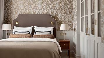 A bedroom with a large bed, two bedside tables, a nightstand, and a wardrobe.