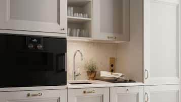 Una cocina con armarios blancos, horno negro, grifo de acero inoxidable y encimera de mármol.