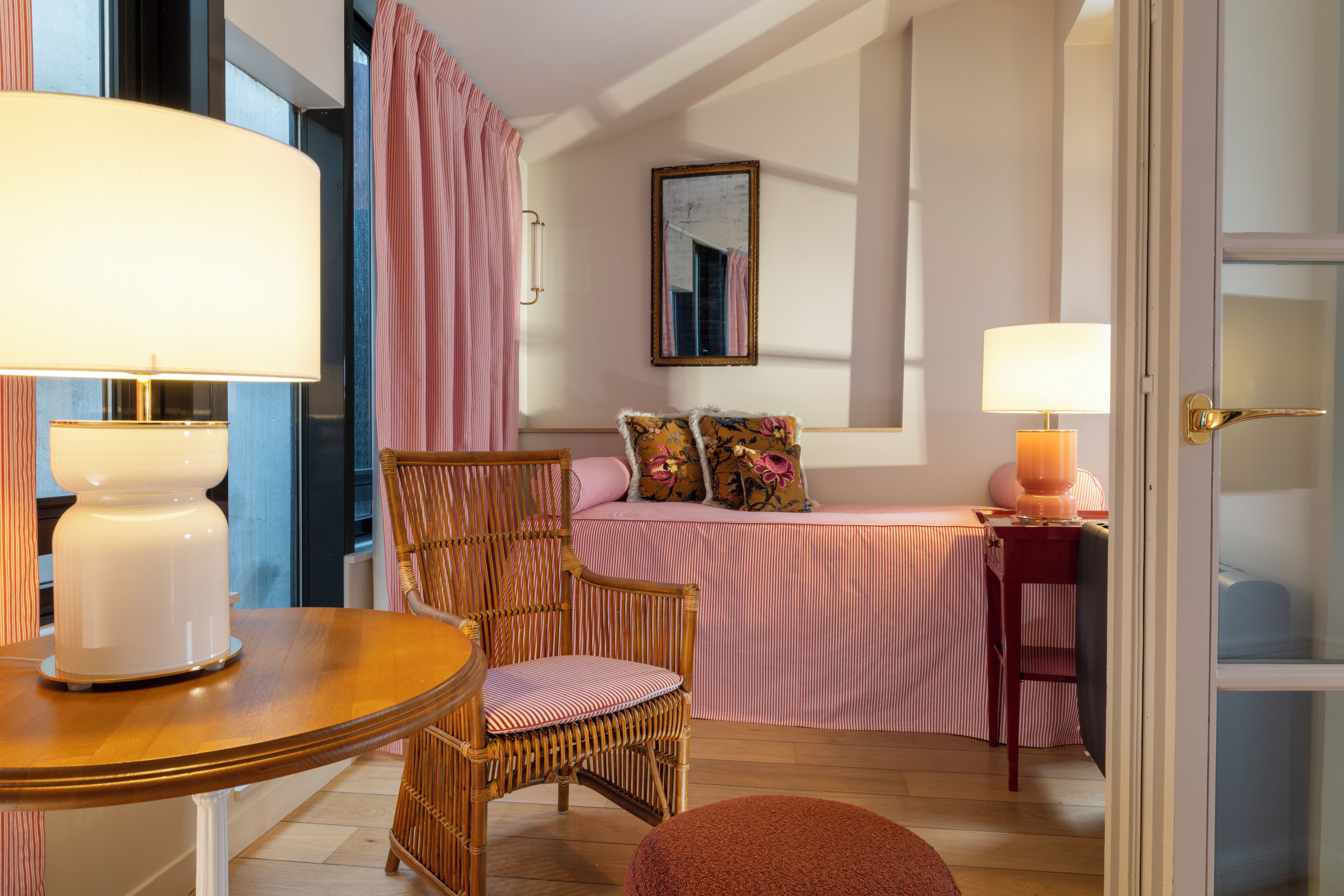 A room with a bed, a chair, a table, and a lamp.