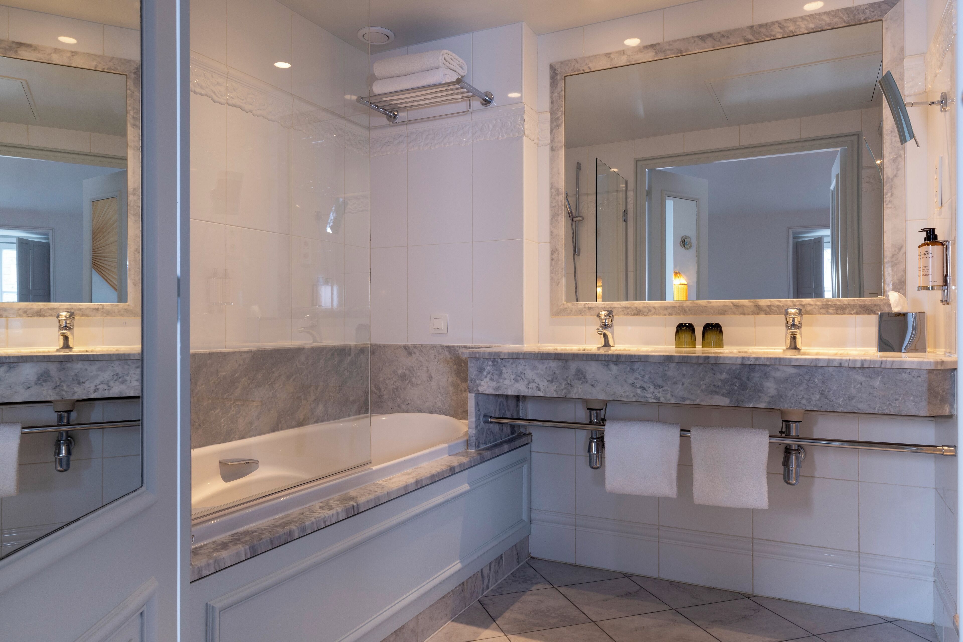 A modern bathroom with a large bathtub, a separate shower area, and a vanity with a mirror.