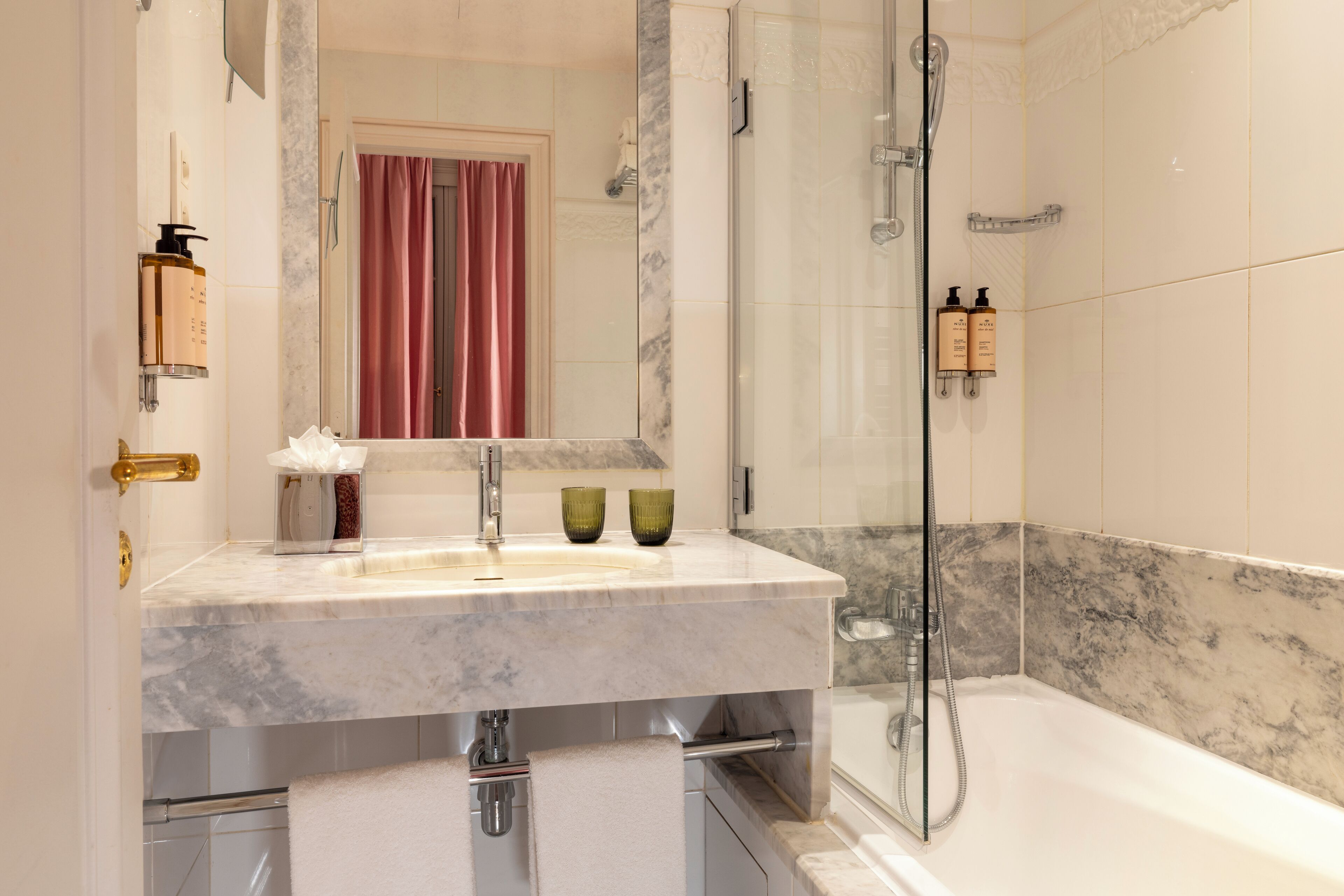 A bathroom with a marble sink, a glass shower enclosure, and a bathtub.