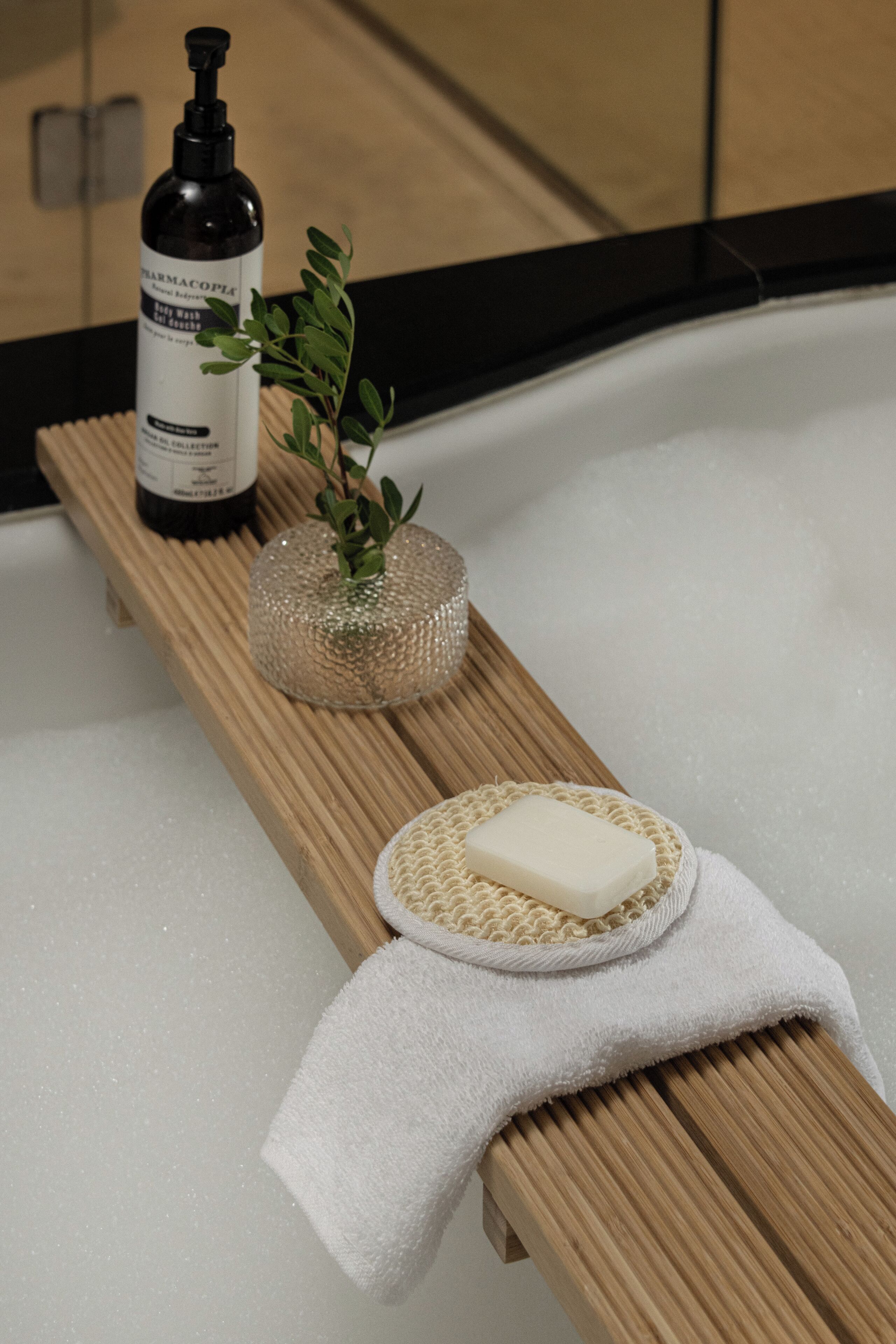A wooden bench with a bottle of skincare product, a soap bar, and a decorative plant.