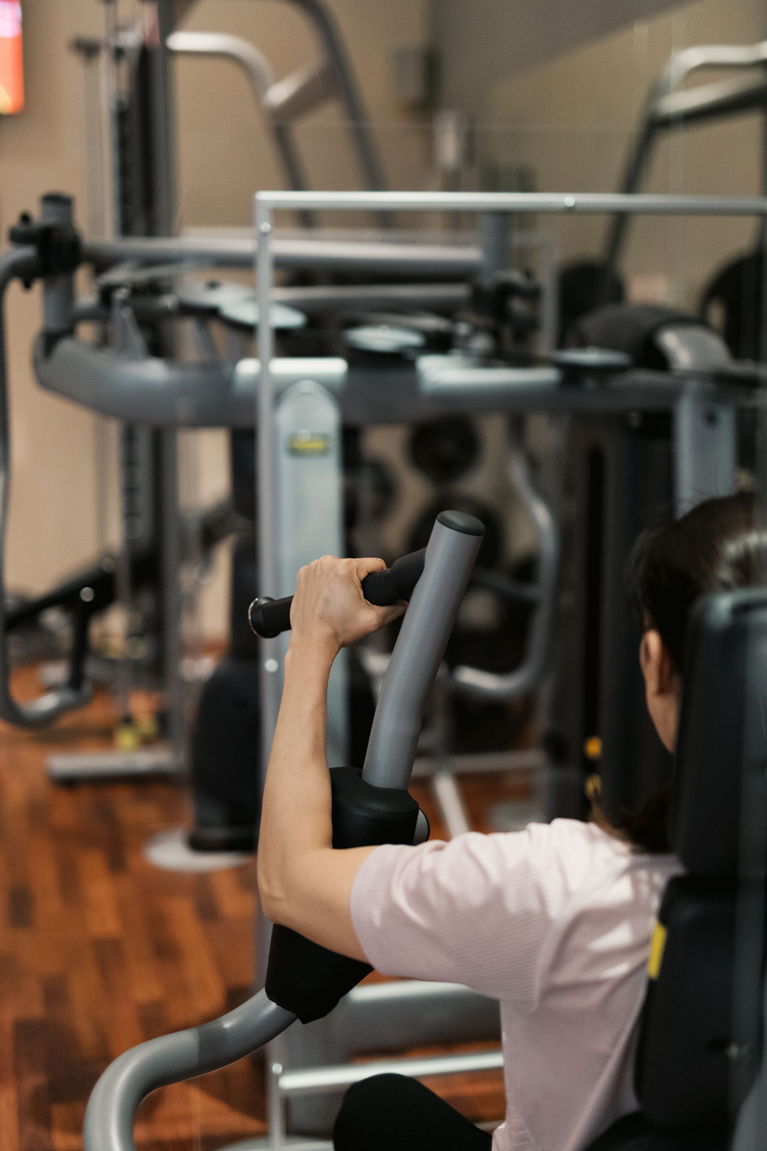 Een sportschool met trainingsapparatuur, waaronder een roeiapparaat en een leg press.