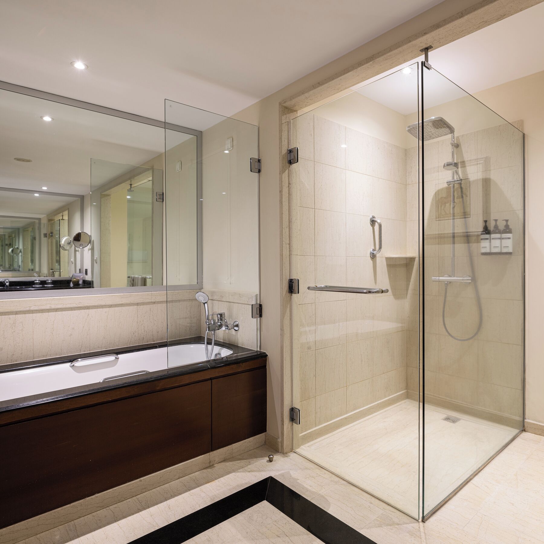 A modern bathroom with a glass-enclosed shower, a large mirror, and a dark wooden vanity.