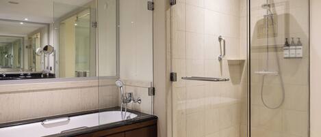 A modern bathroom with a glass-enclosed shower, a large mirror, and a dark wooden vanity.