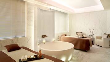Relax in a serene spa room with a bathtub, massage table, and comfortable seating area.