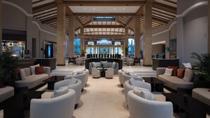 A spacious lobby with a central seating area, a reception desk, and large windows providing natural light. - Hyatt Regency Thessaloniki (Thermi)