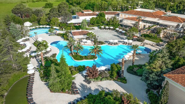 An aerial view of a resort with multiple swimming pools, lounge areas, and lush greenery. - Hyatt Regency Thessaloniki (Thermi)