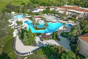 Vista aérea de un complejo turístico con varias piscinas, zonas de descanso y abundante vegetación.
