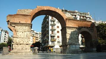 Uma estrutura arqueada histórica em ambiente urbano, com edifícios modernos ao fundo.