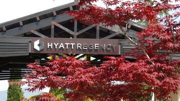 A sign for the Hyatt Regency hotel with a view of red maple leaves in the foreground.