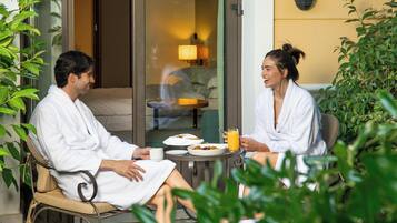 Dos personas con batas blancas sentadas en una mesa con platos de comida y un vaso de zumo de naranja.