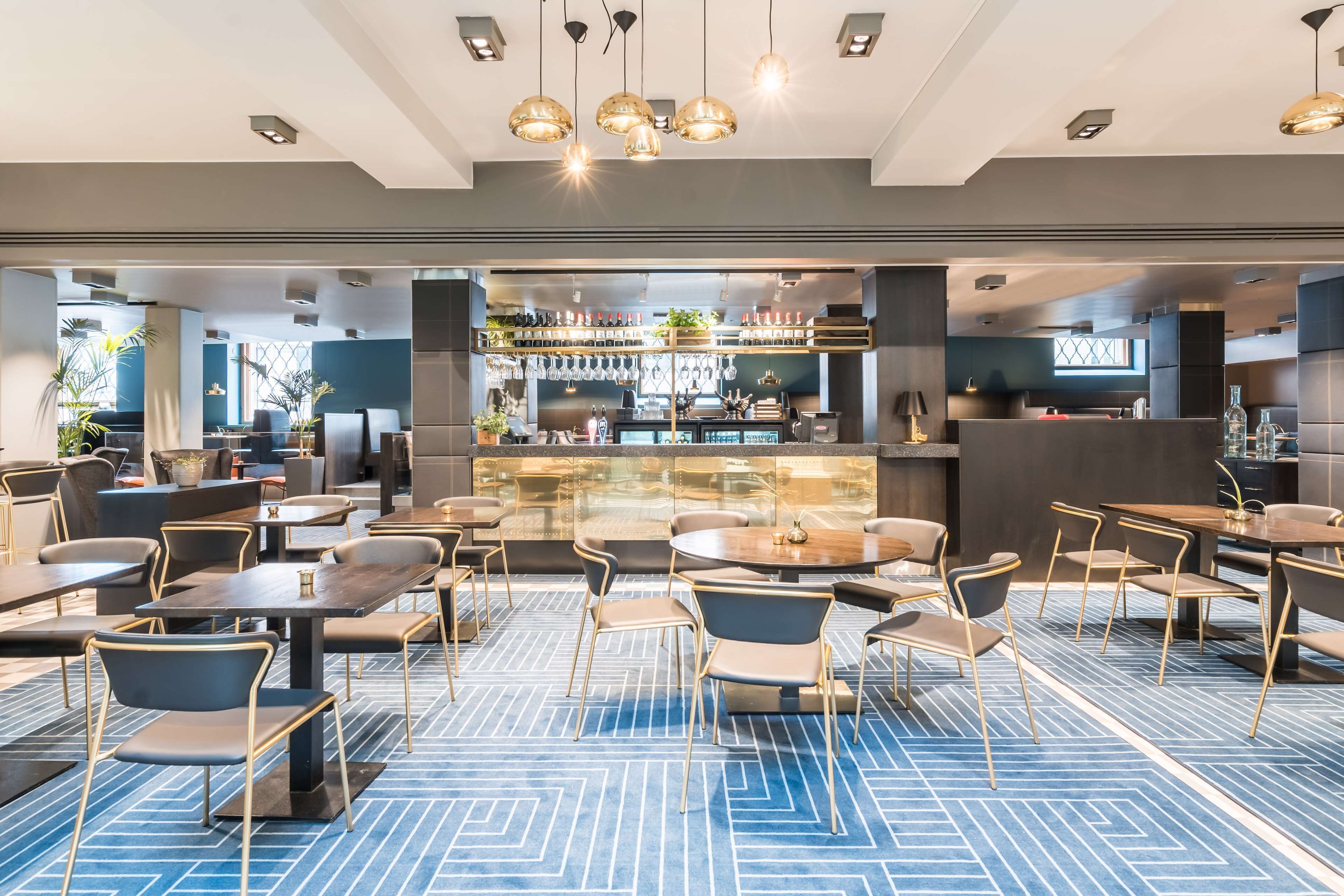 Een moderne hotel lobby met een bar, zithoekjes en een kamerbreed tapijt.