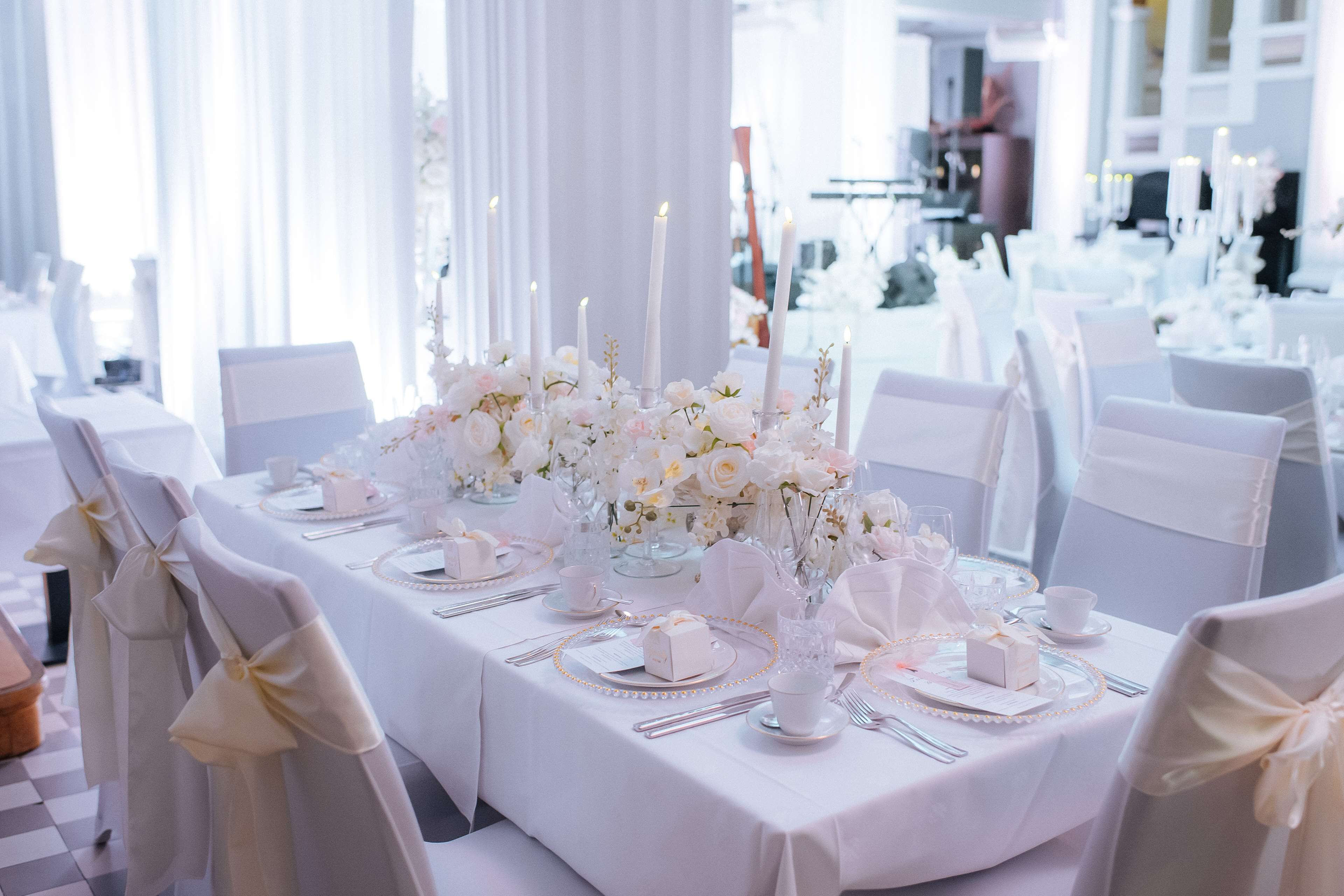 Ein Festtisch, gedeckt mit weißen Tischdecken, Kerzen und Blumenarrangements.