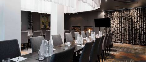 A conference room with a long table set for meetings, equipped with chairs, water bottles, and notepads.