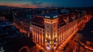 Un edificio con letrero que dice 'PLAZA', varios pisos y una calle en su parte delantera.