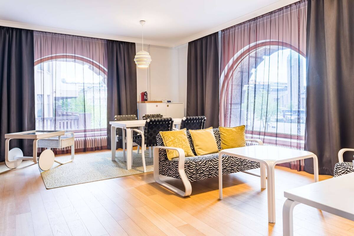 A modern living room with a sofa, a dining table, and a kitchen area.