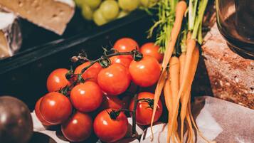 A display of fresh produce including tomatoes, carrots, and grapes.