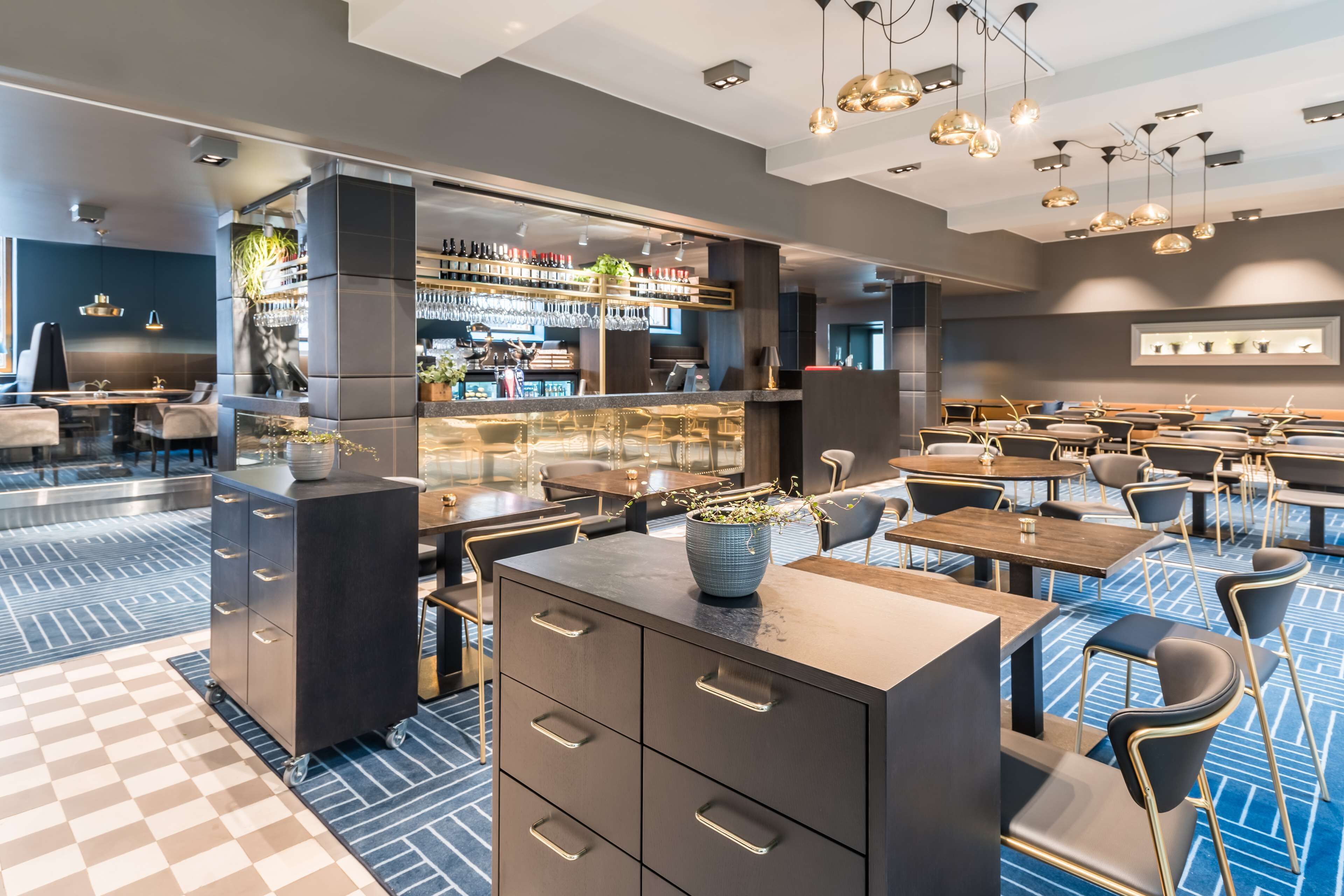 Un restaurant moderne doté d’un bar, de plusieurs tables et d’un comptoir d’accueil.