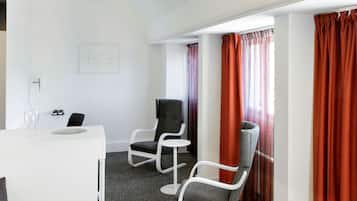 A room with a white desk, two chairs, and a window with red curtains.