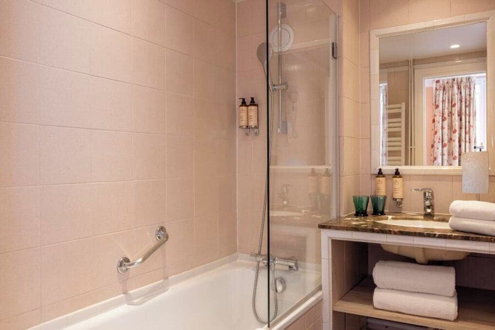 Un baño moderno con ducha de vidrio, bañera blanca y tocador con espejo.