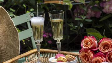 Ett bord med två champagneglas, en korg med macarons och en bukett rosor.
