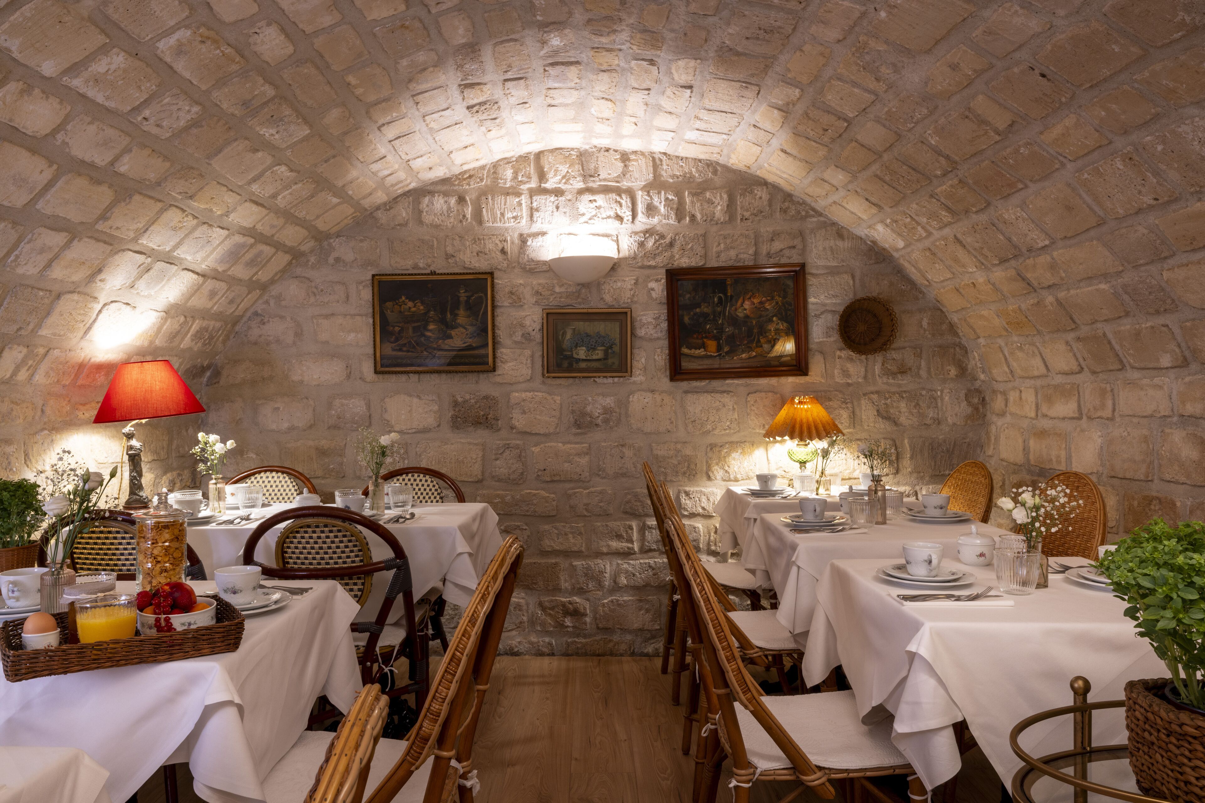 Un espace repas avec des murs en pierre, des chaises en bois et des tables dressées pour le repas.