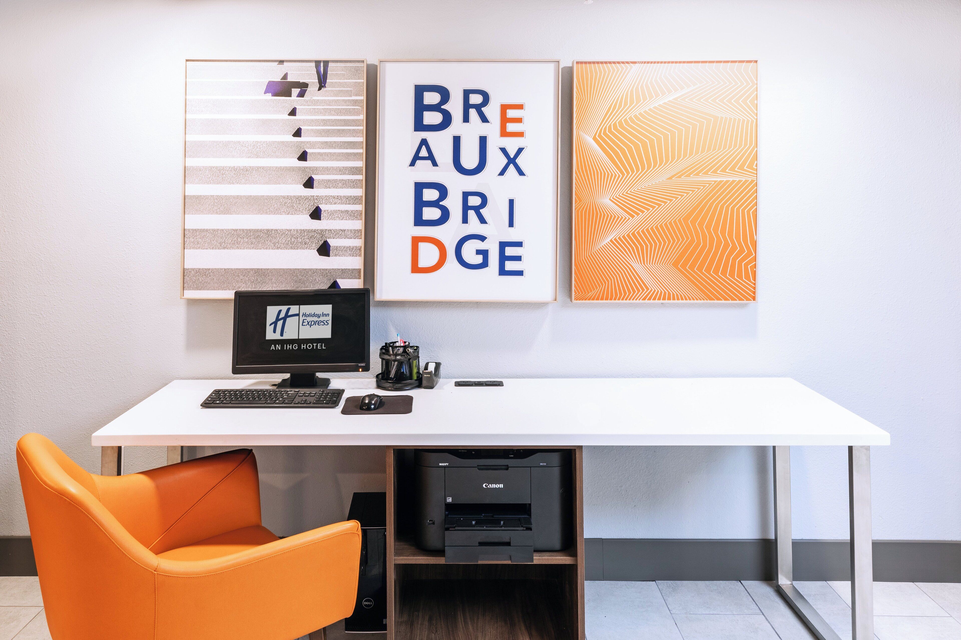 A hotel reception desk with a computer, printer, and a framed sign that reads "BREAUX BRIDGE".
