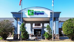 A Holiday Inn Express building with a prominent entrance, two flags, and a clear blue sky.