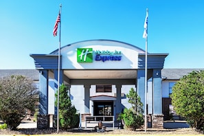 A Holiday Inn Express building with a prominent entrance, two flags, and a clear blue sky. - Holiday Inn Express Breaux Bridge by IHG (Breaux Bridge)