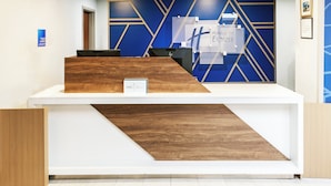A reception desk with a blue geometric wall design and a wooden accent.