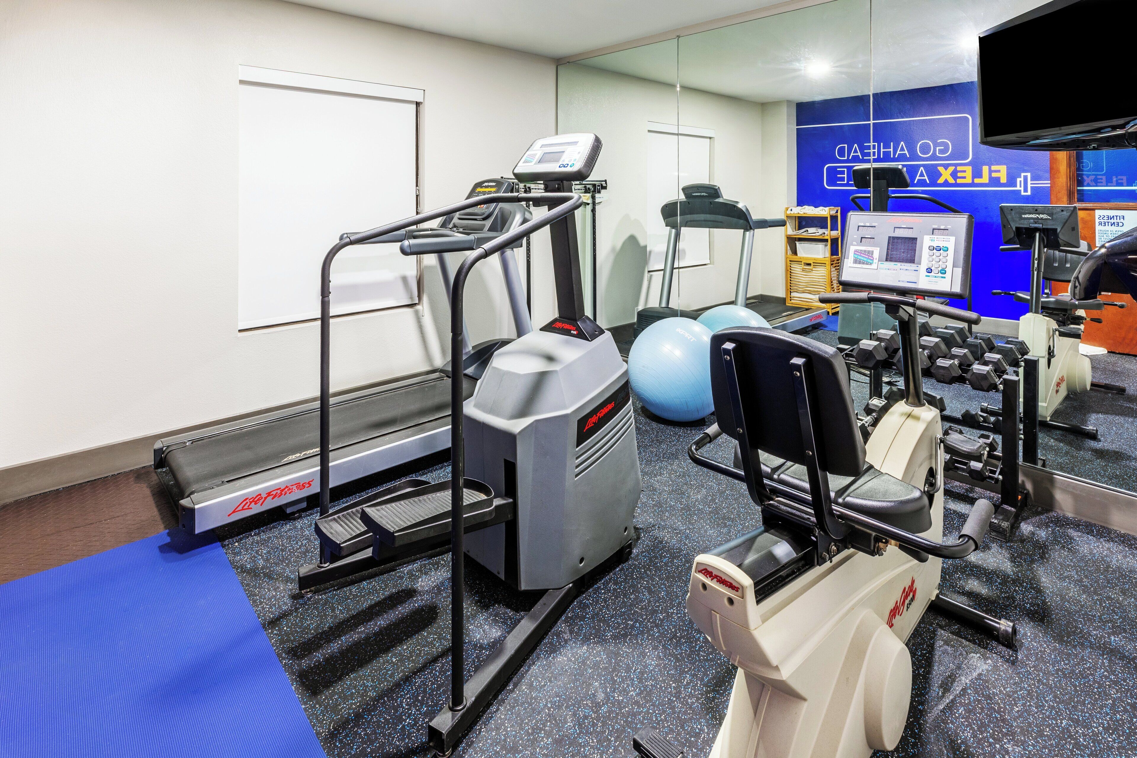 A gym with treadmills, a stationary bike, and free weights.