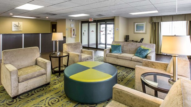 A hotel lobby with seating arrangements, a reception desk, and a view of the parking area through the glass doors. - Quality Inn Fitzgerald (Fitzgerald)