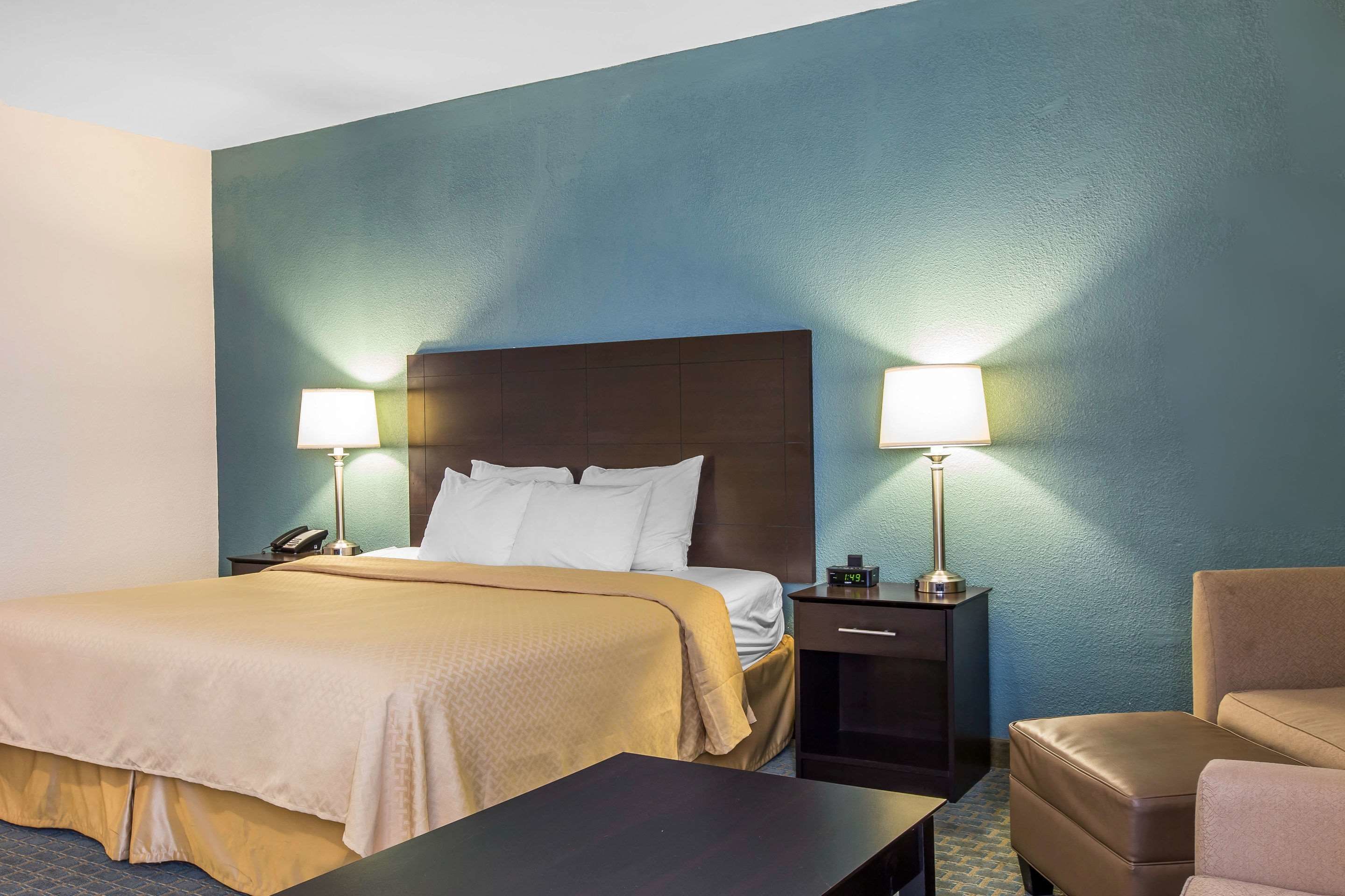 Une chambre d’hôtel comprenant un lit, des tables de chevet, une commode, une chaise et un bureau.