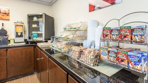 A breakfast buffet area with cereal, waffles, and a coffee machine. - Quality Inn Fitzgerald (Fitzgerald)