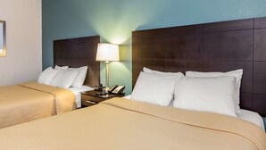 A hotel room with two beds, a nightstand with a lamp, and a phone. - Quality Inn Fitzgerald (Fitzgerald)