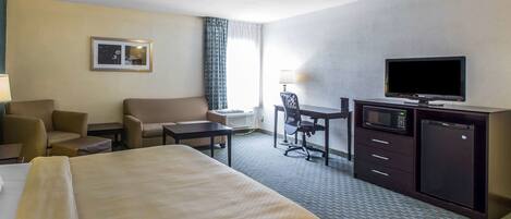 A hotel room with a bed, a desk, a television, a microwave, and a refrigerator.