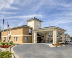 Un hotel con fachada color beige, un acceso cubierto y banderas estadounidenses.