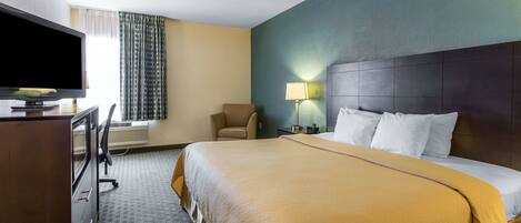 Une chambre d’hôtel comprenant un lit, un bureau avec une télévision, une chaise et une lampe.