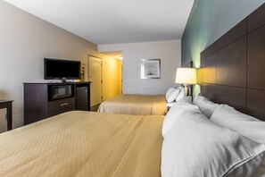 A hotel room with two beds, a television, a microwave, and a desk.
