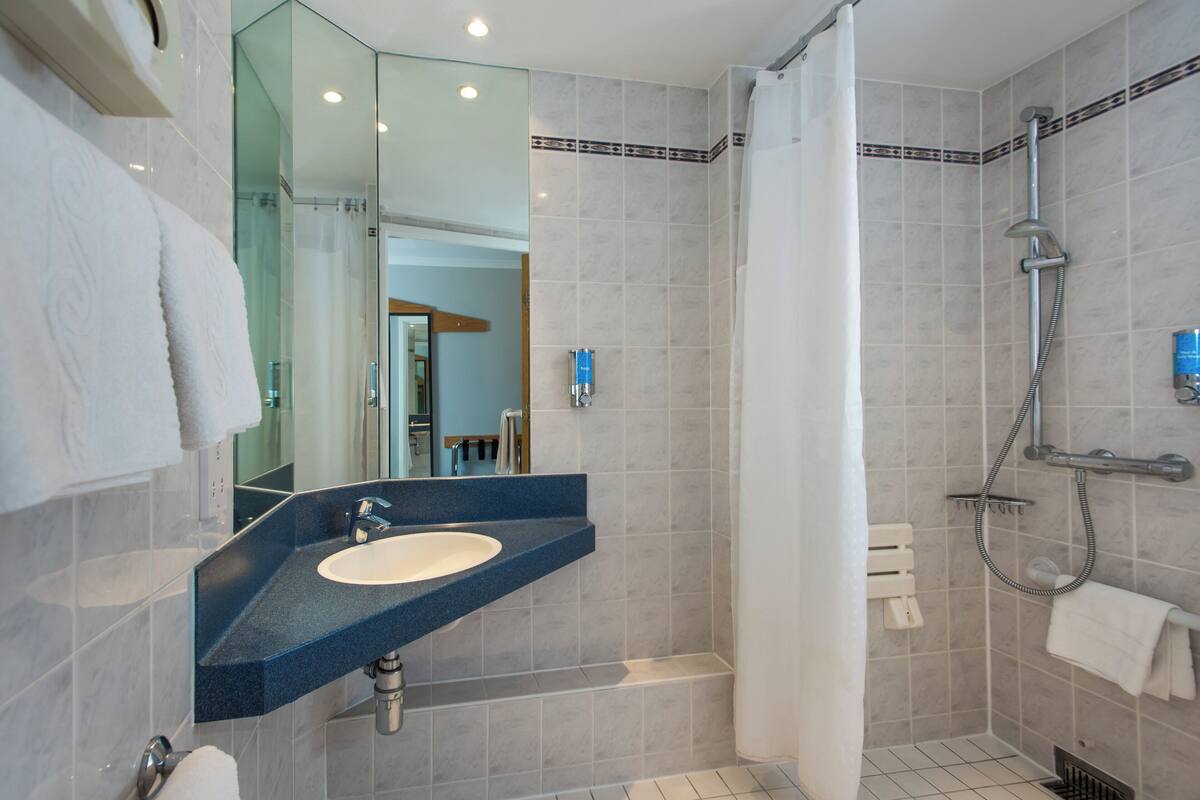 A modern bathroom with a sink, mirror, shower, and bathtub.