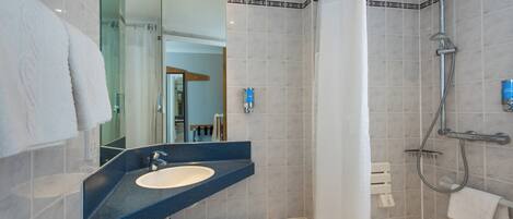 A modern bathroom with a sink, mirror, shower, and bathtub.