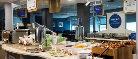 A buffet area with various food options, including cereal, fruits, and pastries.